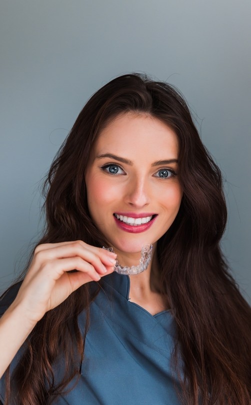 Dentist in Liverpool holding Invisalign braces
